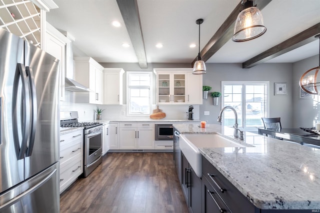 kitchen featuring white cabinetry, appliances with stainless steel finishes, beamed ceiling, and an island with sink