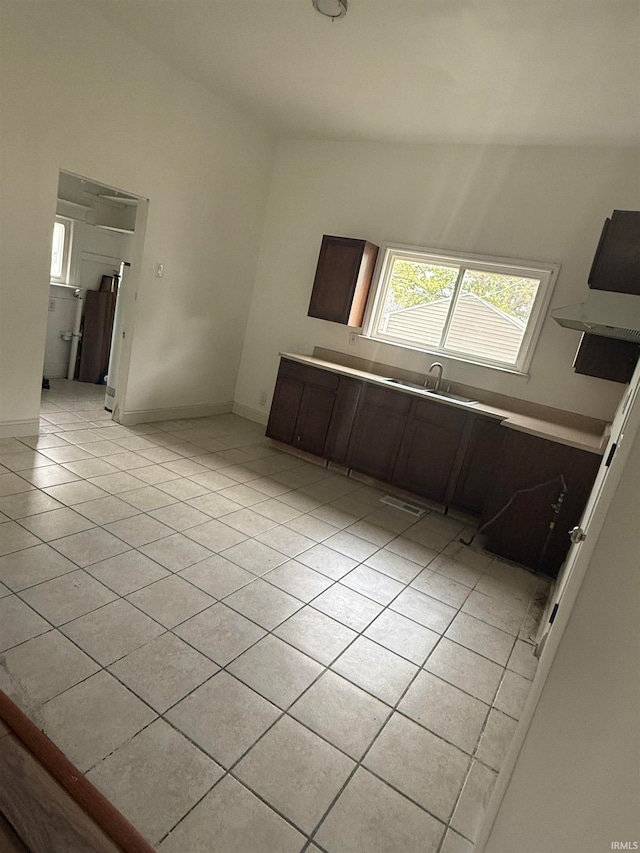 kitchen with vaulted ceiling, dark brown cabinets, and light tile patterned floors