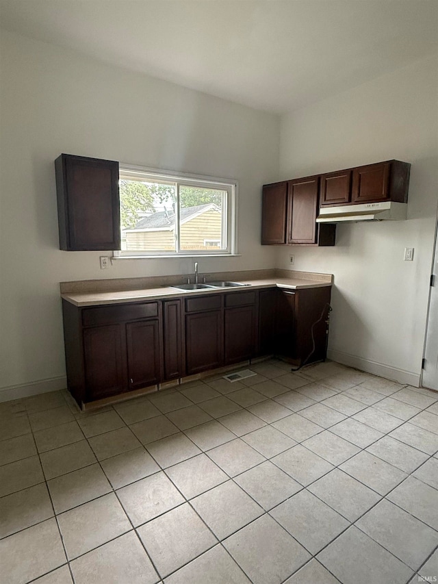 kitchen with sink, light tile patterned flooring, and dark brown cabinets