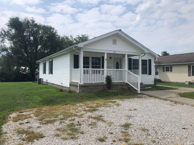 view of front facade featuring covered porch, cooling unit, and a front lawn