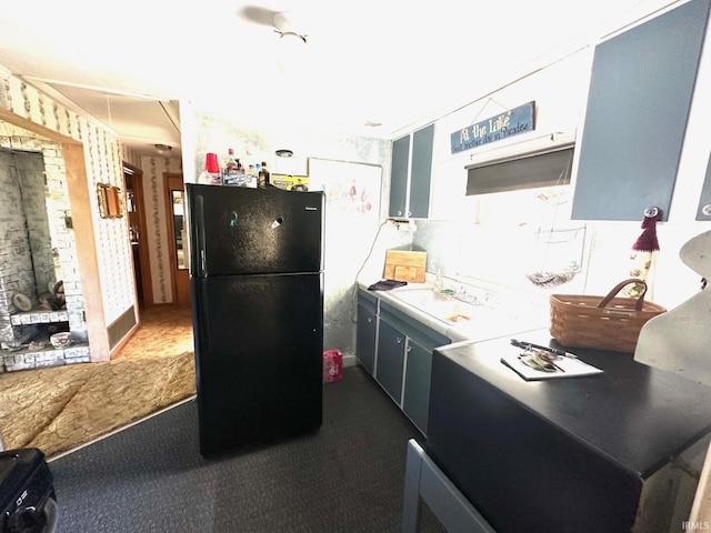 kitchen with black refrigerator, dark colored carpet, and sink