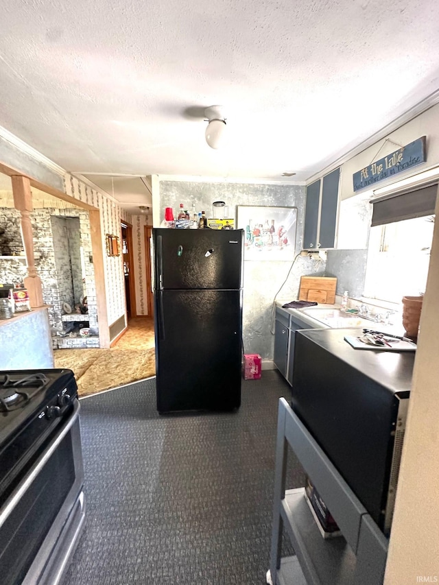 kitchen with black fridge, stainless steel gas stove, a textured ceiling, and sink