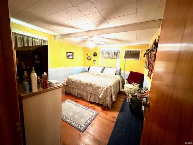 bedroom featuring ceiling fan, hardwood / wood-style floors, and a wall mounted air conditioner