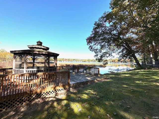 dock area featuring a gazebo, a deck with water view, and a lawn