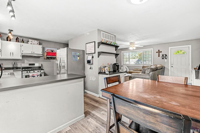 kitchen featuring kitchen peninsula, white cabinets, ceiling fan, light hardwood / wood-style flooring, and stainless steel appliances