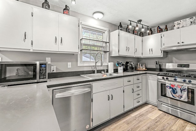 kitchen with sink, a textured ceiling, stainless steel appliances, white cabinets, and light hardwood / wood-style flooring