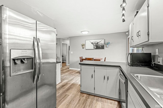 kitchen with kitchen peninsula, stainless steel appliances, light wood-type flooring, and white cabinets