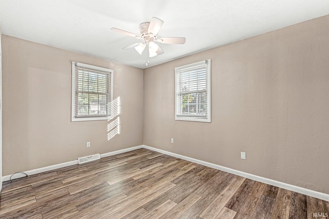 spare room with ceiling fan, wood-type flooring, and a wealth of natural light