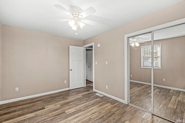 unfurnished bedroom with wood-type flooring, a closet, and ceiling fan