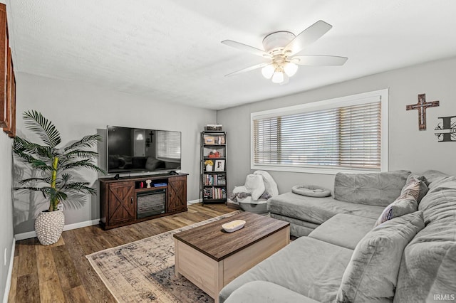 living room featuring a textured ceiling, dark wood-type flooring, and ceiling fan