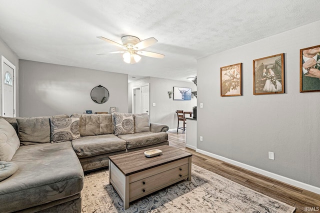 living room featuring a textured ceiling, light wood-type flooring, and ceiling fan