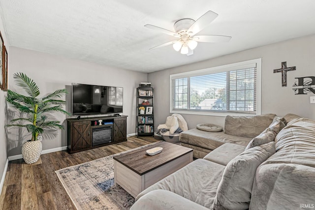 living room with dark wood-type flooring, ceiling fan, and a textured ceiling