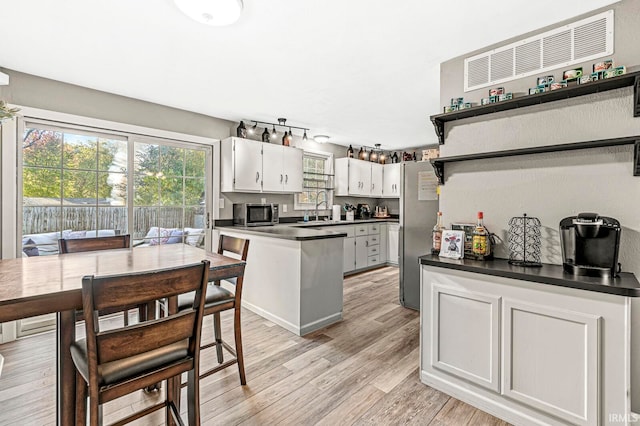 kitchen featuring sink, stainless steel appliances, light hardwood / wood-style flooring, and white cabinets