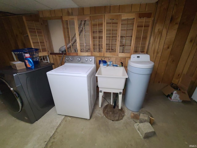 clothes washing area with wood walls, washer / clothes dryer, and sink