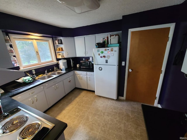 kitchen featuring sink, white cabinetry, white fridge, and a textured ceiling