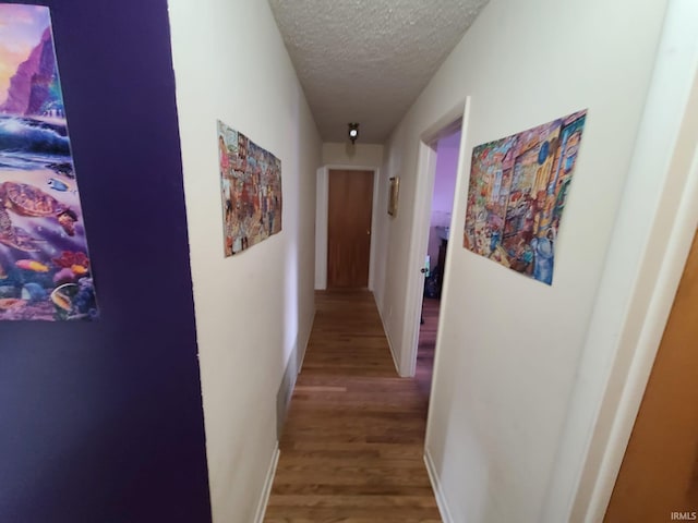 hall with a textured ceiling and hardwood / wood-style flooring