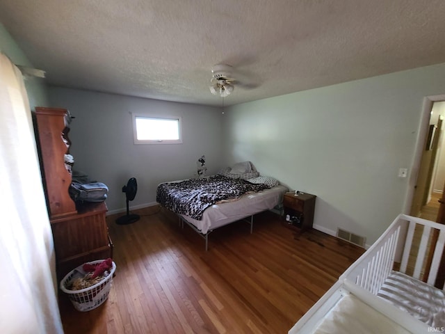 bedroom with dark wood-type flooring, ceiling fan, and a textured ceiling