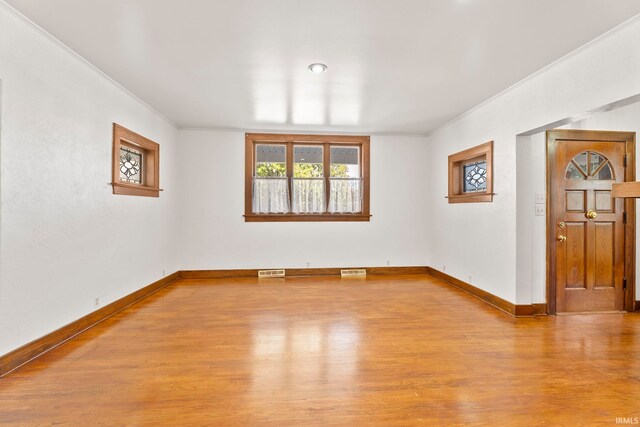 unfurnished room with ornamental molding and light wood-type flooring