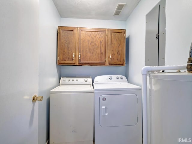 washroom with cabinets, washer and dryer, and electric panel