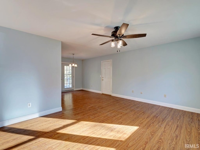 unfurnished room with ceiling fan with notable chandelier and hardwood / wood-style floors