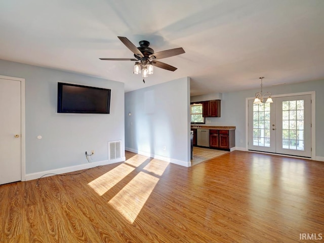 unfurnished living room featuring light hardwood / wood-style flooring and ceiling fan with notable chandelier