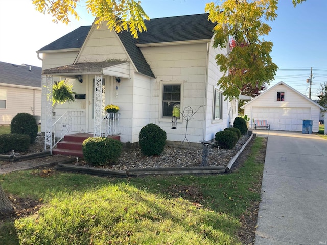 bungalow-style house with a front yard, a garage, and an outbuilding