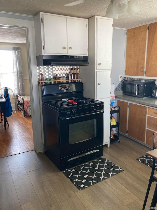 kitchen with white cabinets, tasteful backsplash, ceiling fan, light hardwood / wood-style flooring, and black appliances