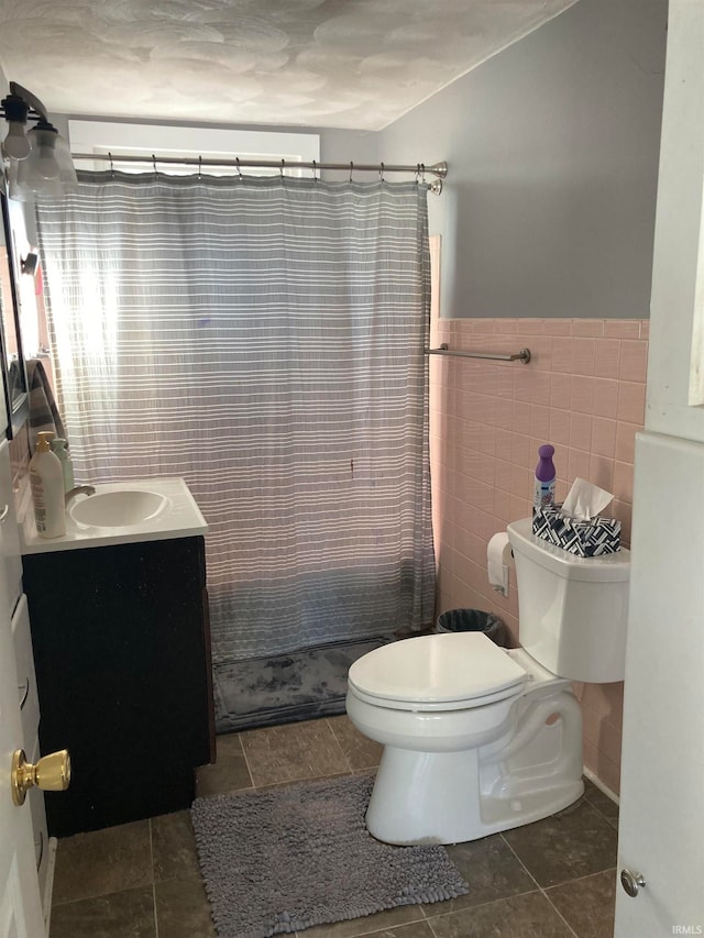 bathroom with tile patterned floors, toilet, vanity, curtained shower, and tile walls