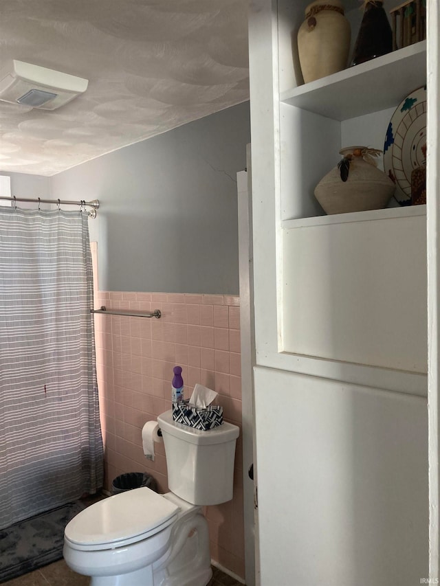 bathroom featuring tile walls, a shower with curtain, and toilet