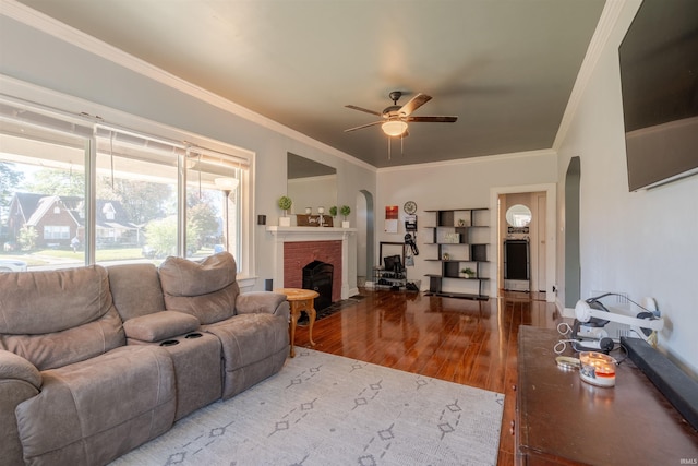 living room featuring ornamental molding, a brick fireplace, hardwood / wood-style flooring, and ceiling fan