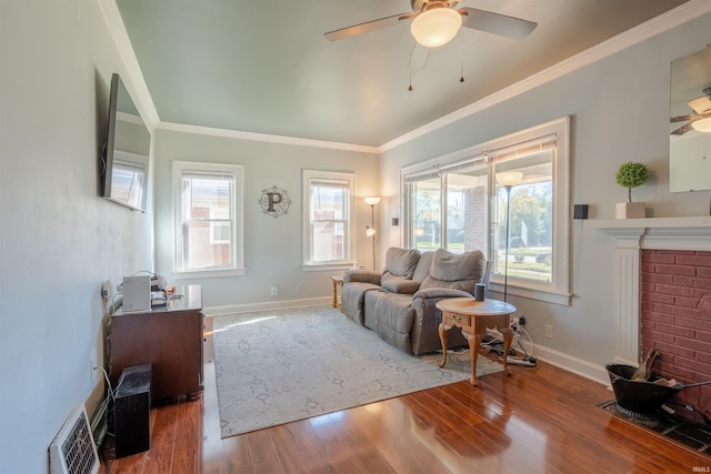 living room with crown molding, a fireplace, hardwood / wood-style flooring, and ceiling fan