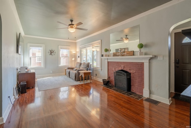 living room featuring hardwood / wood-style floors, a brick fireplace, crown molding, and ceiling fan