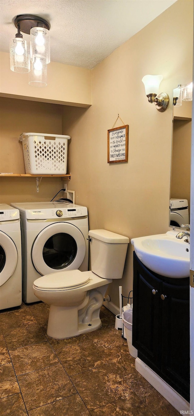 laundry area featuring sink, a textured ceiling, and washer and clothes dryer