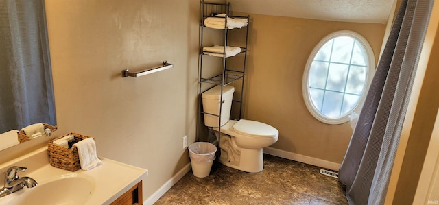 bathroom with vanity, toilet, and a textured ceiling