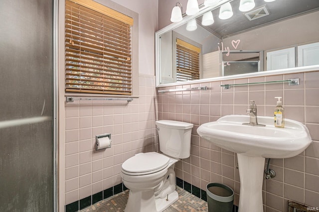 bathroom featuring toilet, tile patterned floors, and tile walls