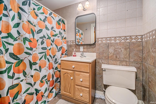 bathroom with toilet, tile patterned flooring, vanity, curtained shower, and tile walls