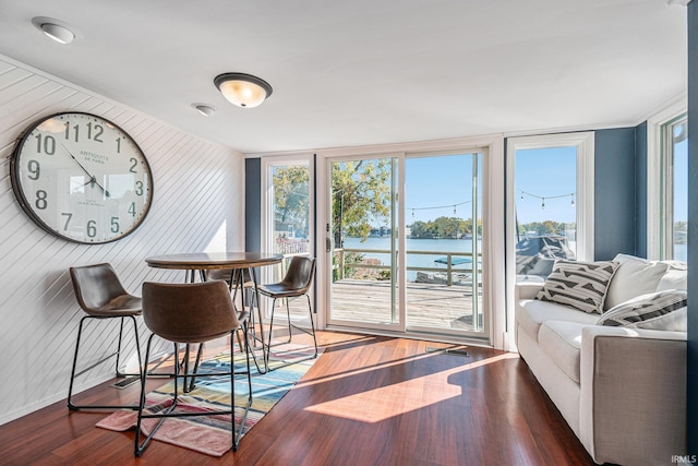 dining area featuring wooden walls, a water view, and dark hardwood / wood-style floors