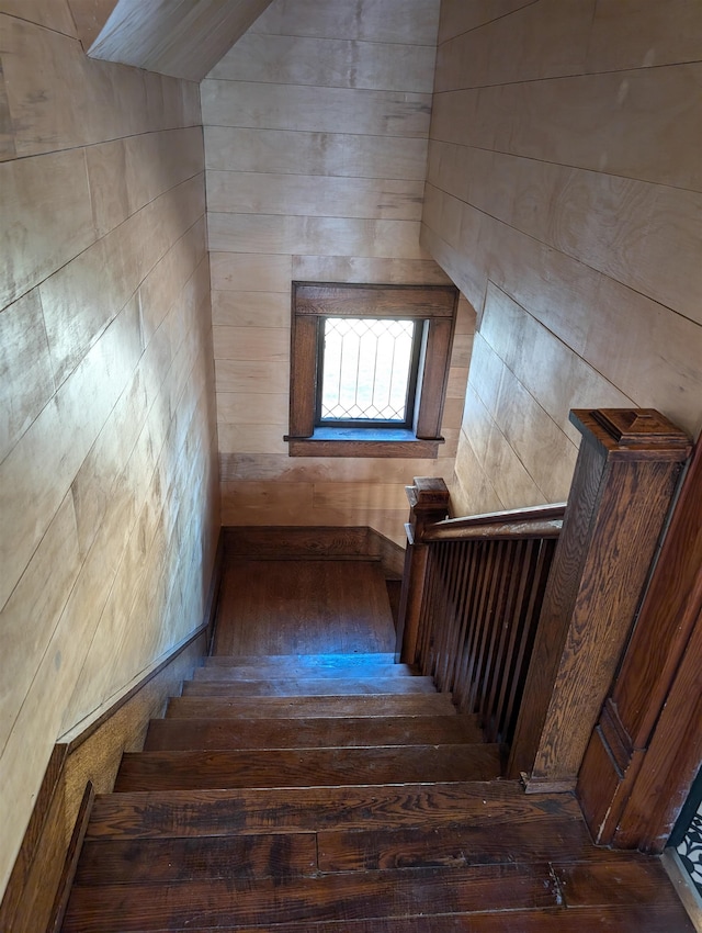 staircase featuring wood-type flooring and wooden walls