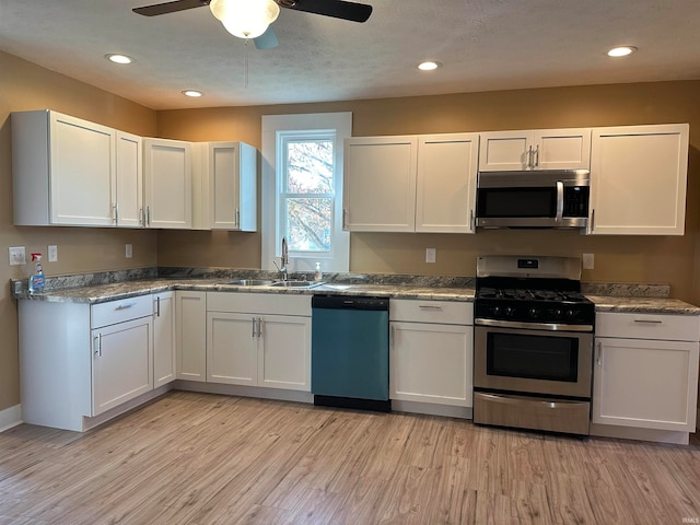 kitchen with white cabinets, ceiling fan, light wood-type flooring, sink, and stainless steel appliances