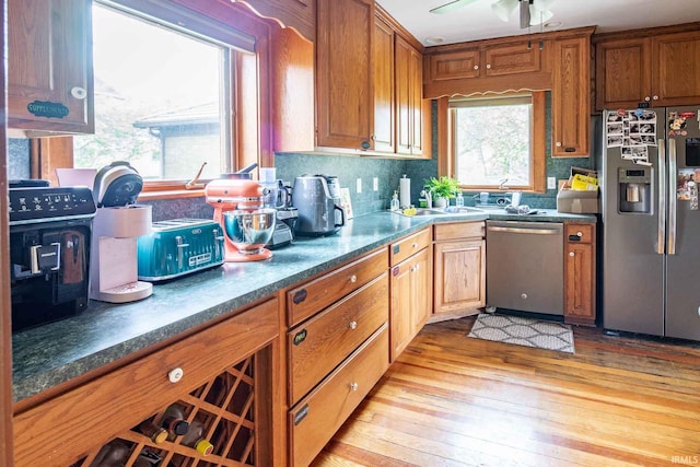 kitchen with light hardwood / wood-style flooring, sink, ceiling fan, backsplash, and appliances with stainless steel finishes