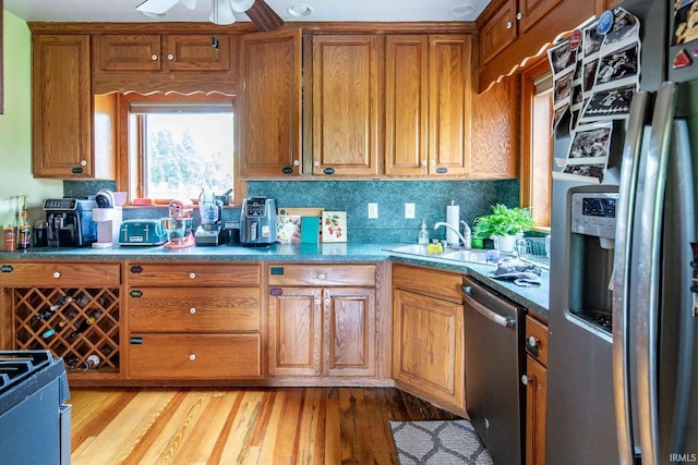 kitchen featuring sink, appliances with stainless steel finishes, tasteful backsplash, ceiling fan, and light hardwood / wood-style flooring