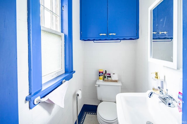 bathroom with tile walls, tile patterned floors, sink, and toilet