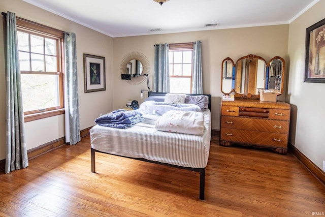 bedroom with hardwood / wood-style flooring, multiple windows, and crown molding