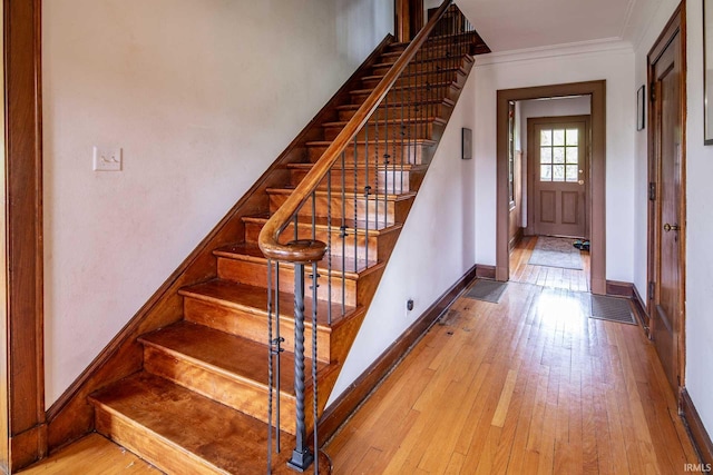 stairway with hardwood / wood-style flooring and crown molding