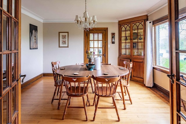 dining space with ornamental molding, light wood-type flooring, a notable chandelier, and french doors