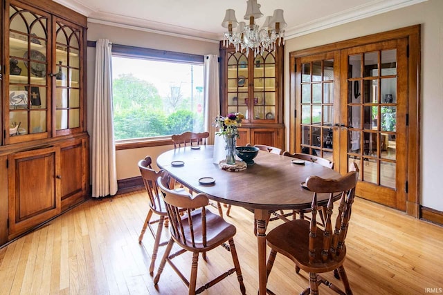 dining area featuring french doors, a notable chandelier, light hardwood / wood-style floors, and crown molding