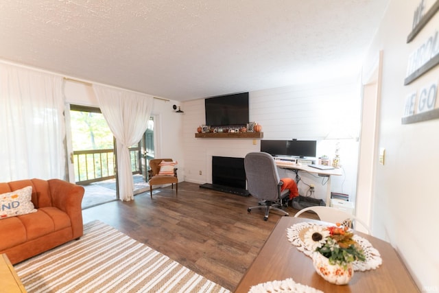 home office featuring a large fireplace, hardwood / wood-style flooring, and a textured ceiling