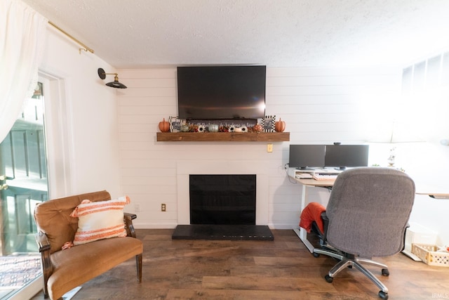 office space with wooden walls, a fireplace, dark hardwood / wood-style floors, and a textured ceiling