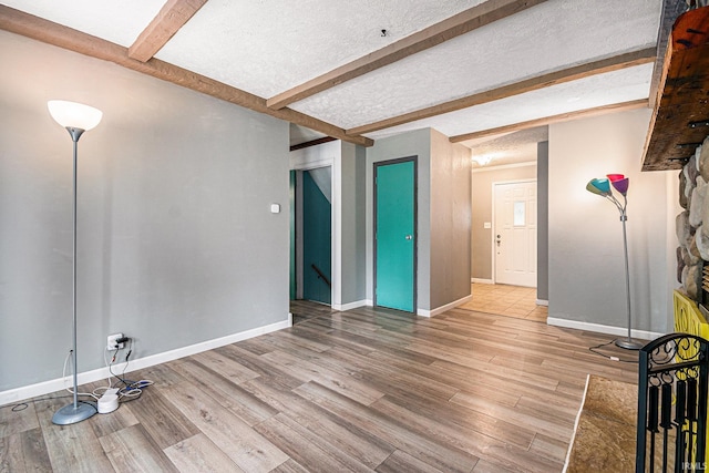 spare room with a textured ceiling, beamed ceiling, and wood-type flooring