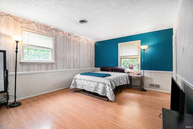 bedroom featuring a textured ceiling, wood-type flooring, and multiple windows